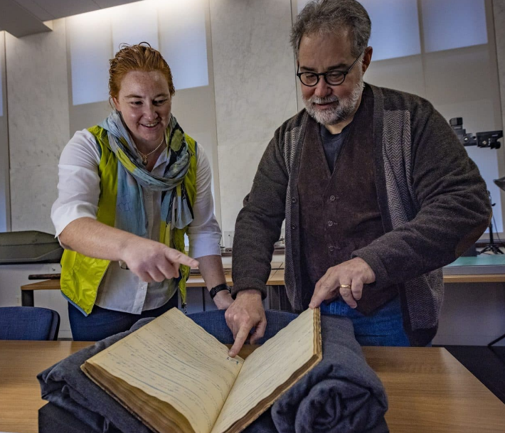 Caroline Ummenhofer and Timothy Walker Caroline Ummenhofer, an oceanographer at the Woods Hole Oceanographic Institution, and Timothy Walker, history professor at UMass Dartmouth, with a logbook from the Ship Lion, which sailed to the South Pacific in the 1840s. (Jesse Costa/WBUR)